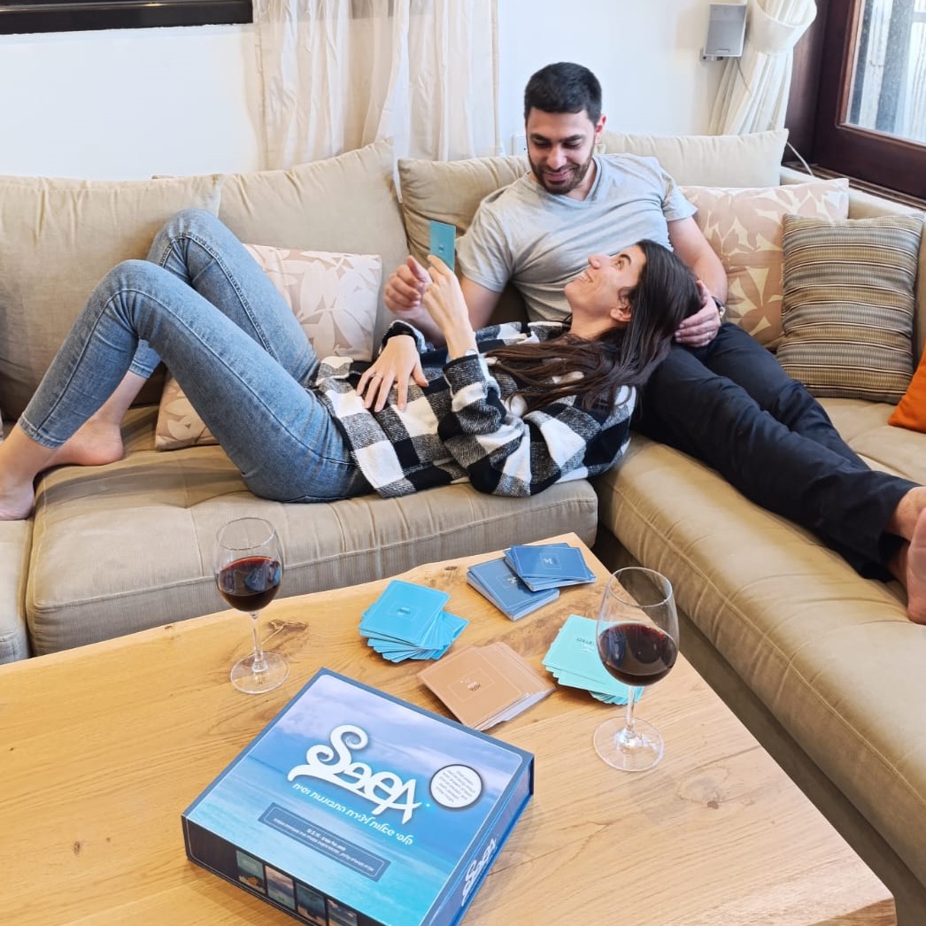 זוג על הספה עם ערכת SeeA, יין על השולחן, שיחה זוגית קרובה בערב
